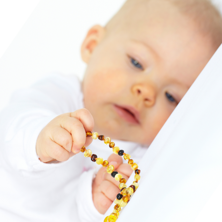 Collier Ambre Bébé dans les mains d'un bébé